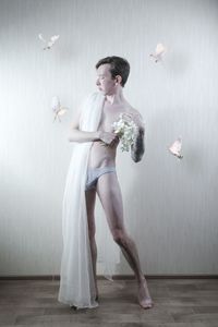 Portrait of young man with birds standing against wall