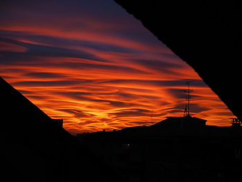 Low angle view of silhouette city against orange sky