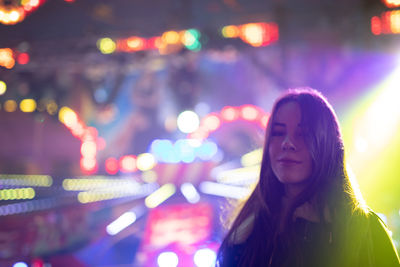 Portrait of a smiling young woman in city at night