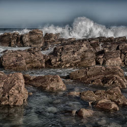 Scenic view of rocks in sea against sky