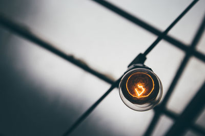 Low angle view of illuminated light bulb against sky