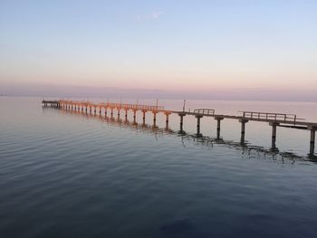 Wooden posts in sea against clear sky