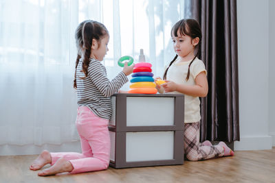 Sisters playing with multi colored toys at home