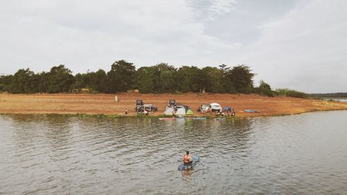 People in boat on lake against sky