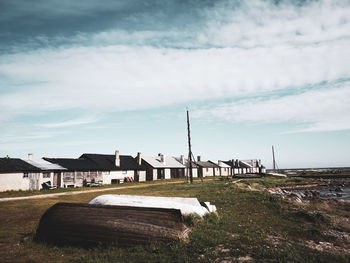 Scenic view of field by houses against sky