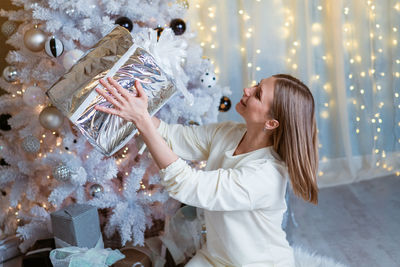 Christmas, new year. beautiful woman in light dress and socks sits on floor