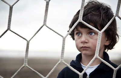 Close-up of cute boy looking through net