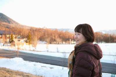 Woman standing in snow against sky during winter