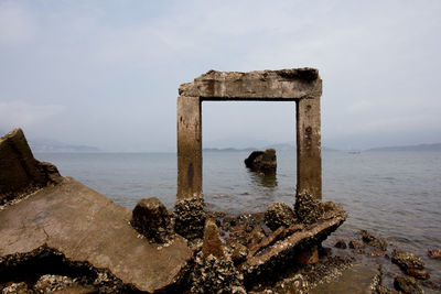 Scenic view of man made formations on sea against cloudy sky