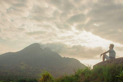 Man standing on rock against sky