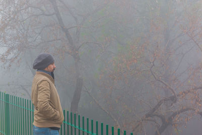 Side view of man wearing warm clothing looking away during foggy weather