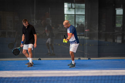 Monitor teaching padel class to man, his student - trainer teaches boy how to play padel 