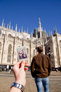 Woman holding photograph of couple by church