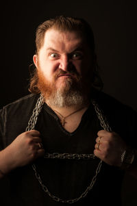 Portrait of man holding camera over black background