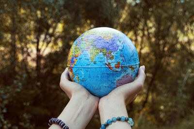 Woman holding globe against trees