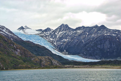 Snow covered mountains against cloudy sky