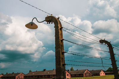 Low angle view of telephone pole by building against sky