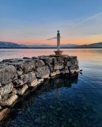 Lighthouse by lake leman against sky during sunset