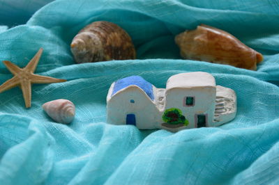 High angle view of house and seashells on turquoise fabric