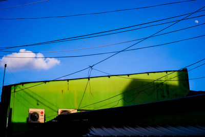 Low angle view of electricity pylon against clear blue sky