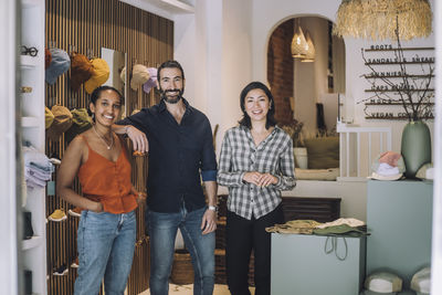 Portrait of smiling female and male sales colleagues standing together at fashion store