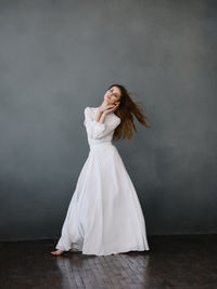 Woman looking away while standing against white wall