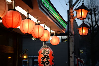 Low angle view of illuminated lanterns hanging by building