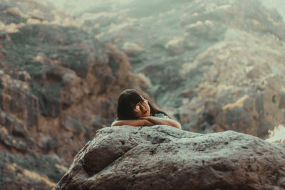 Young woman on rock against sky