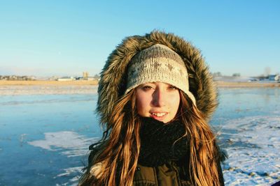 Portrait of smiling young woman with warm clothing against sky