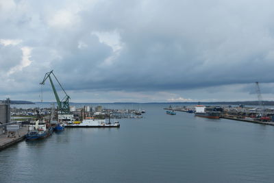 Boats in harbor against cloudy sky