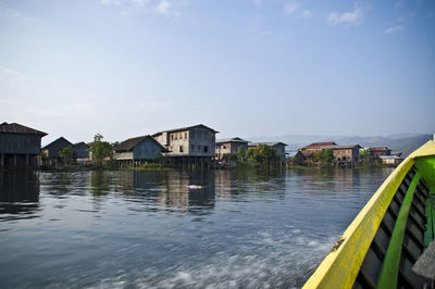 Houses by river against sky