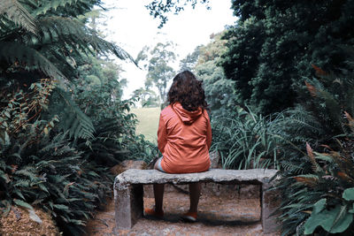 Rear view of woman sitting against trees