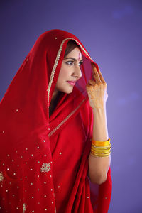 Beautiful indian woman in red sari against purple background