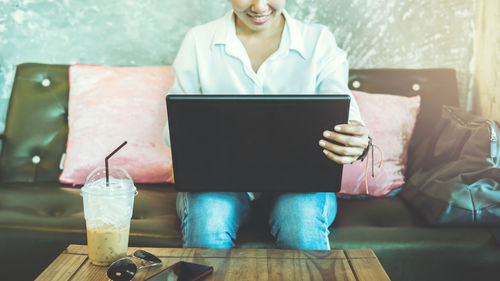 Midsection of woman using mobile phone while sitting on table