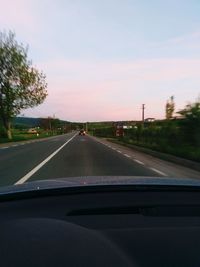 Road seen through car windshield during sunset