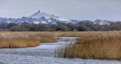 Scenic view of lake by snow field against sky