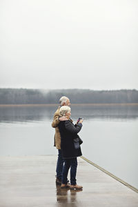 Full length of woman standing in lake against sky during winter