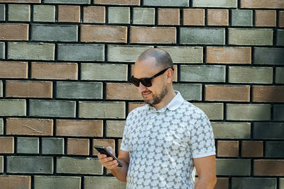 Side view of young man standing against wall