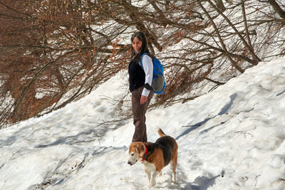 Portrait of young woman with dog on snow covered field