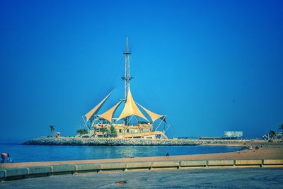 Tourists at harbor against clear blue sky