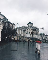 People walking on street in city against sky