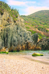 Scenic view of rocks by sea against sky