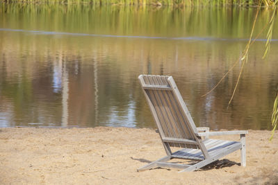 Empty chair on beach against lake