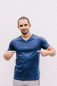 Portrait of man gesturing while standing against white wall