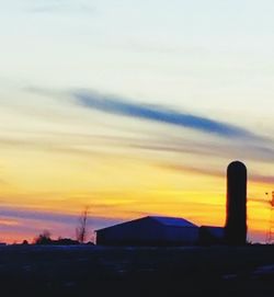 Silhouette factory against sky during sunset