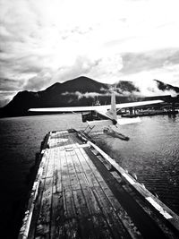 Pier on sea against cloudy sky