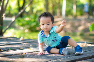 Cute boy looking away while sitting on land