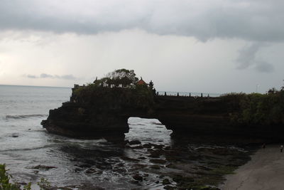 Rock formation on beach against sky