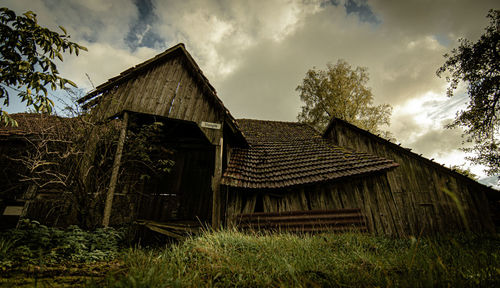 Old wooden house on field against sky