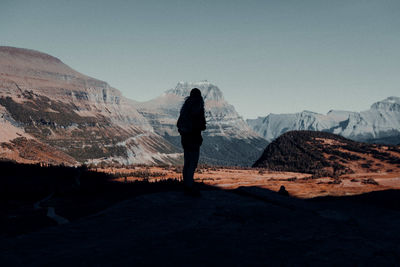 Rear view of man standing on mountain against sky